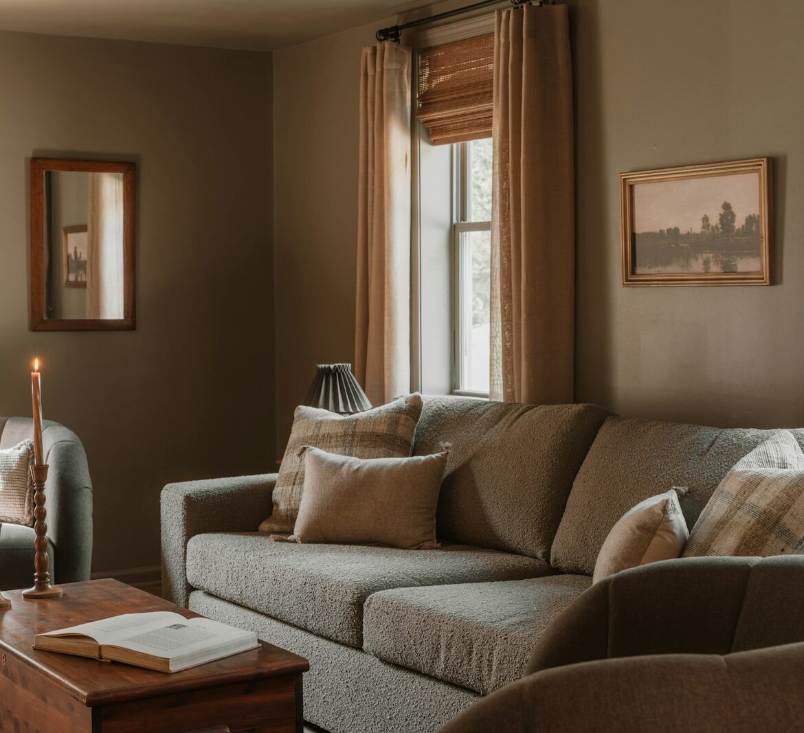 Cosy living room with a sofa, candles and long curtains in warm evening light