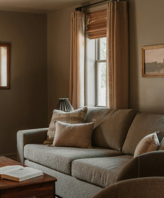 Cosy living room with a sofa, candles and long curtains in warm evening light