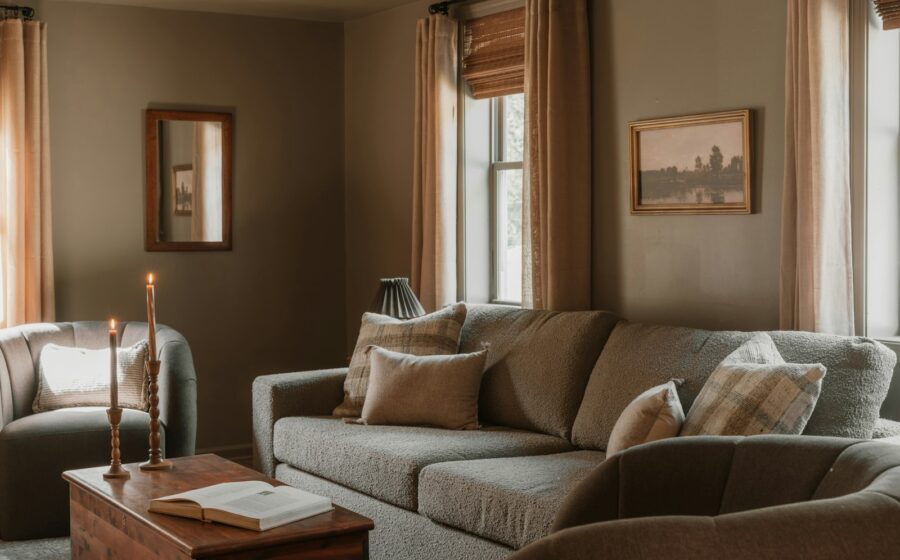 Cosy living room with a sofa, candles and long curtains in warm evening light