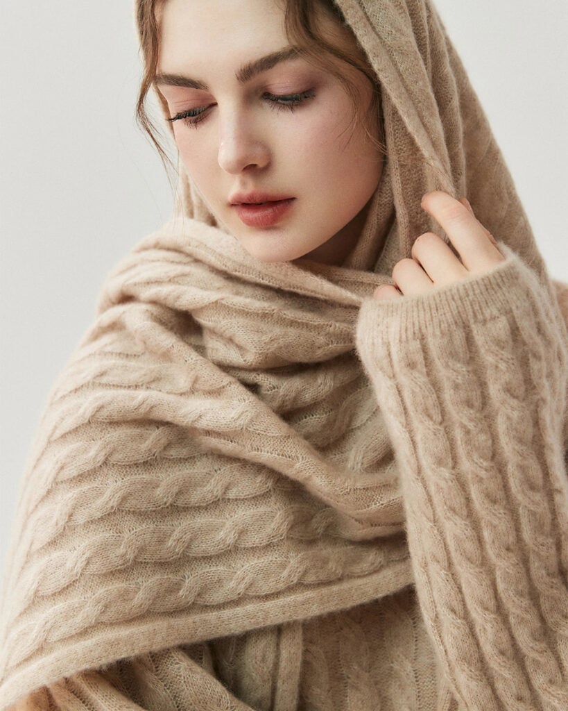 Woman wrapped in a beige cable knit cashmere and silk scarf